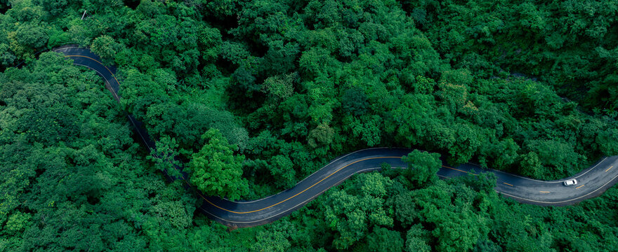 Aerial view of a road in the middle of the forest , road curve construction up to mountain