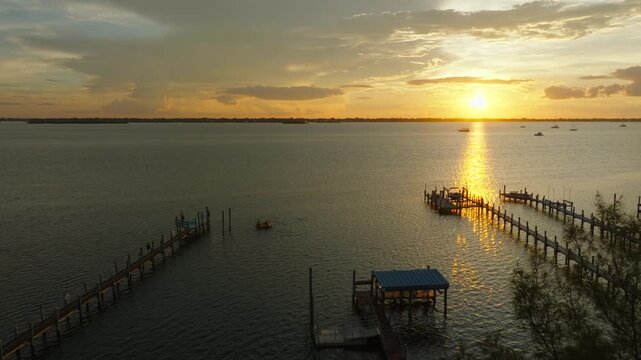 Aerial Sunset Over Stuart, Florida Waterfront Docks and Palm Trees With Golden Reflection