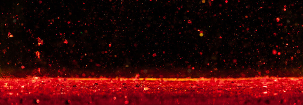 Macro photo of red Christmas glitter sparks bokeh on black background