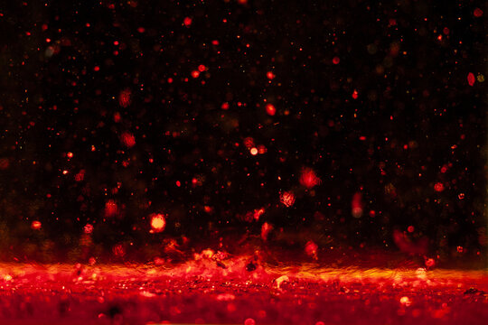 Macro photo of red Christmas glitter sparks bokeh on black background