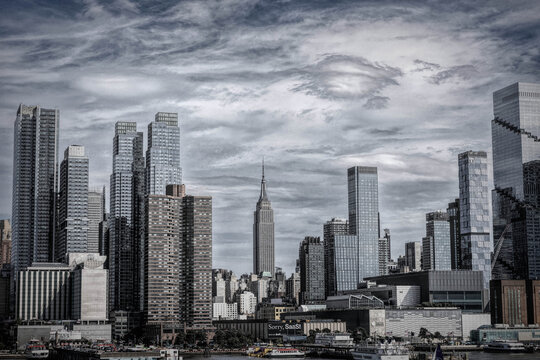 ew York City Rising Above the Hudson River Waterfront.** The Empire State Building Anchors a Modern Manhattan Skyline.