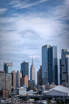 ew York City Rising Above the Hudson River Waterfront.** The Empire State Building Anchors a Modern Manhattan Skyline.