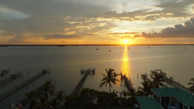 Aerial Sunset Over Stuart, Florida Waterfront Docks and Palm Trees With Golden Reflection