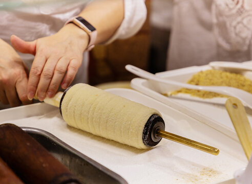 Hands preparing traditional pastry on rolling pin with ingredients nearby