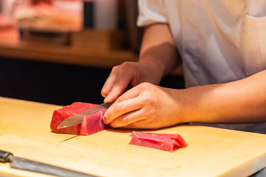 Chef slicing fresh tuna fillet on wooden cutting board in kitchen