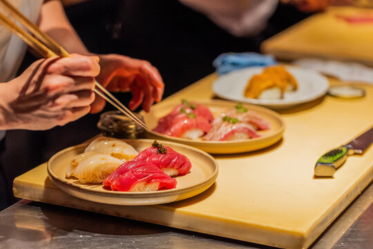 Sushi chef preparing fresh sushi on wooden counter with vibrant colors