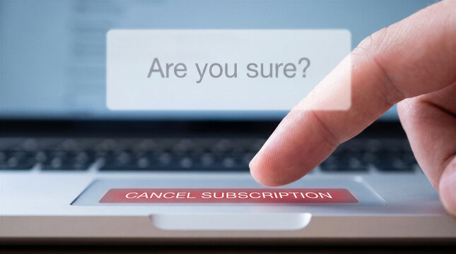 Closeup of a finger pressing a red cancel subscription button on a laptop keyboard with a confirmation prompt on the screen
