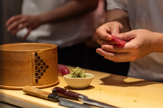 Skilled chef preparing sushi with fresh ingredients and bamboo container