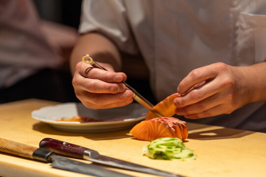 Sushi chef preparing fresh salmon sashimi with precision and care