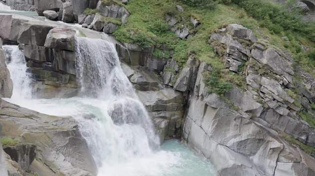 Alternative view of a beautiful two tier alpine waterfall rushing through rocky swiss mountains in summer
