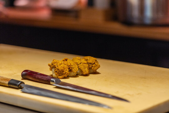 Freshly prepared fried chicken pieces on wooden cutting board with knives