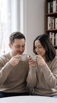 Couple sharing warm morning coffee moment together near home bookshelf