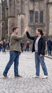 Two friends sharing joyful high five together in historic old town square