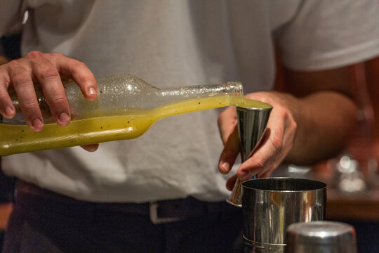 Bartender pouring vibrant cocktail mix into jigger for drink preparation
