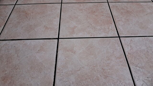 Square beige floor tiles with dark grout lines in interior view