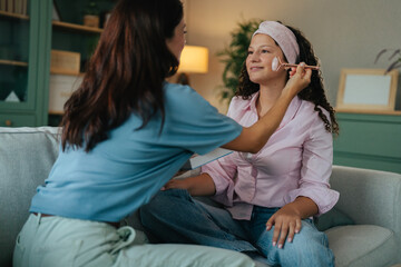Mother applying jade roller for daughter's skin care routine © Miljan Živković