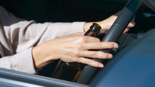 Woman drinking beer while driving a car. Close-up revealing professional female driver recklessly holding beer bottle while operating vehicle, demonstrating hazardous driving behavior