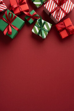 Festive red and green wrapped presents with ribbons for Merry Christmas and Happy New Year celebration on vertical maroon space