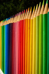 kolorowe pasy, tęczowe prążki, kolorowe kredki z drewna, ogrodzenie w formie kolorowych kredek z drewnianych bali, rainbow stripes, fence made of wooden logs shaped like colorful crayons © kateej
