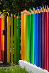 kolorowe pasy, tęczowe prążki, kolorowe kredki z drewna, ogrodzenie w formie kolorowych kredek z drewnianych bali, rainbow stripes, fence made of wooden logs shaped like colorful crayons © kateej