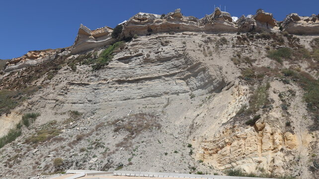 NAZAR&Eacute;, PORTUGAL - SEPTEMBER 8, 2026: General view of Nazar&eacute; coastal town and Atlantic Ocean Layered rock formations on a steep cliff face under a clear blue sky
