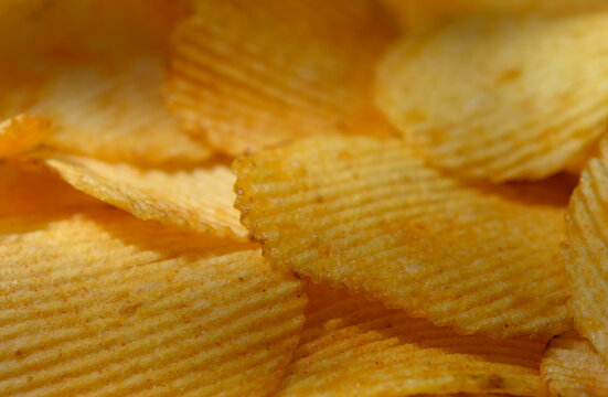 Commercial food photography of a macro background of crispy ridged potato chips with golden texture