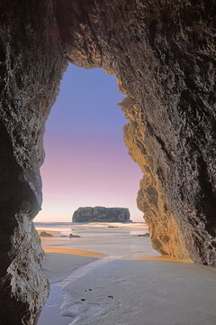 Spectacular sunset on Playa Andr&iacute;n Beach at low tide, Castro Ballota islet in background framed by the mouth of a sea cave. Llanes-Asturias-Spain-084