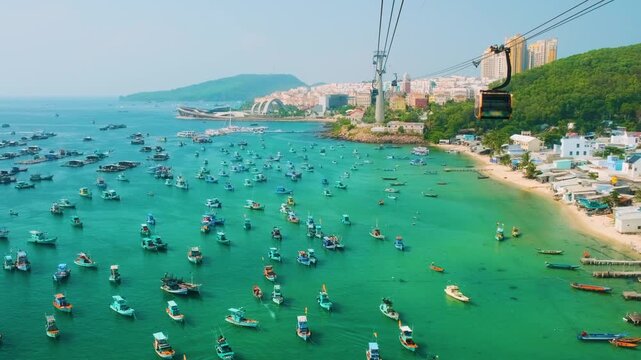 Cable car gondola riding above coastal fishing village and turquoise bay filled with fishing boats on Phu Quoc Island, Vietnam. Tropical travel, island tourism, scenic transportation, coastal landscap