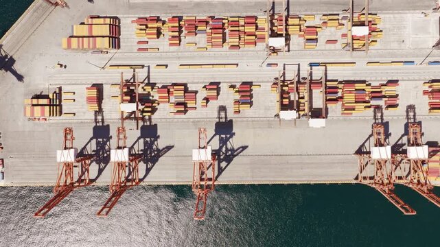 Stunning aerial perspective of an industrial shipping port with gantry cranes moving cargo containers on the dock, showcasing global trade, logistics, and maritime transportation industry