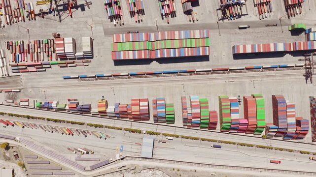 Industrial port terminal with stacks of colorful cargo containers and a freight train moving along the railway tracks, representing global trade, logistics, and supply chain management