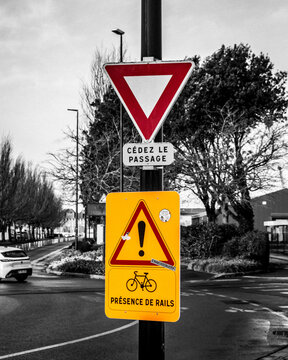 C&eacute;dez le passage and Pr&eacute;sence de rails warning signs on a pole at a street intersection with selective color