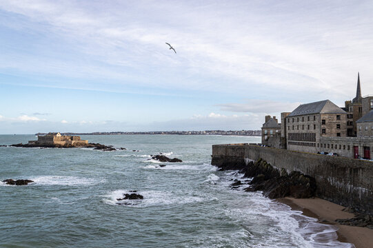 Saint-Malo historic stone ramparts and Fort National offshore fortress with crashing ocean waves, Brittany, France