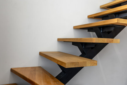 Modern wooden staircase beside white wall. Interior design with copy space.