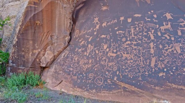 Intricate prehistoric petroglyphs cover a dark desert varnish sandstone panel at Newspaper Rock State Historic Monument in Utah
