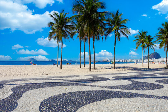 Iconic Copacabana beach boardwalk, palm trees, ocean, under a blue sky, Rio de Janeiro, Brazil. Sunny day travel scene.