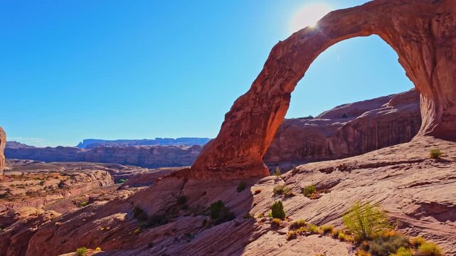 Golden evening light bathes the towering sandstone curve of Corona Arch rising above Bootlegger Canyon near Moab Utah