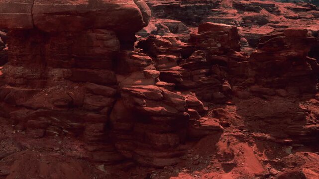 Majestic red rock formations tower in a desolate desert landscape. The warm sunlight illuminates the rugged textures, showcasing natures vibrant hues. A sense of serene isolation lingers in the air.