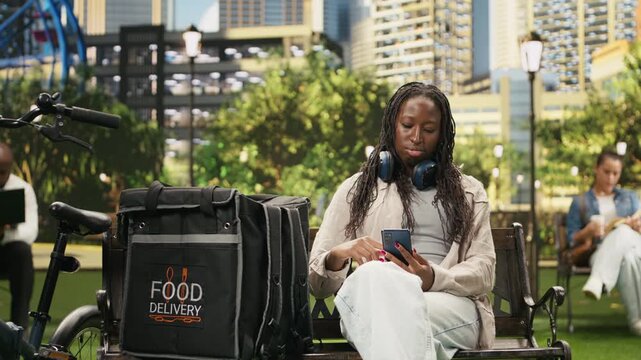 Food delivery courier resting and checking order request on smartphone