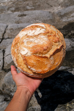 Hand Holding a Rustic Artisan Bread Loaf Outdoors