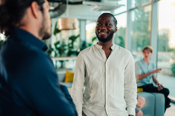 Obraz premium Diverse business professionals collaborating in a modern office, african american man smiling while conversing with colleague