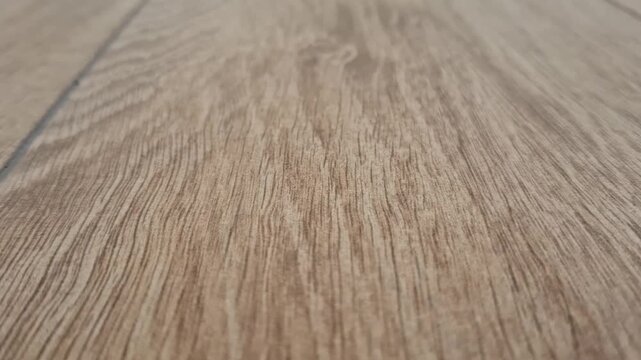 Brown wooden laminate planks lie on the floor indoors. Hardwood flooring texture, interior home renovation, modern flooring materials.