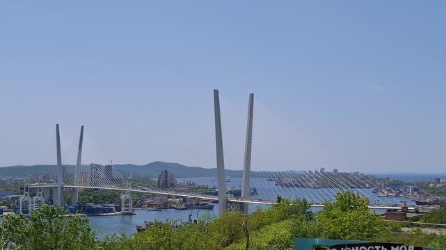 White cable-stayed bridge stands over a sea bay in Vladivostok. Zolotoy bridge cityscape, maritime city infrastructure, Golden horn bay travel destination.
