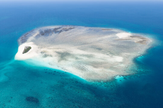 Colorful, turquoise water and coral reef surrounds the tiny, idyllic island of Kaniungan-kecil off the coast of East Kalimantan, Indonesia. This scenic region harbors spectacular marine biodiversity.