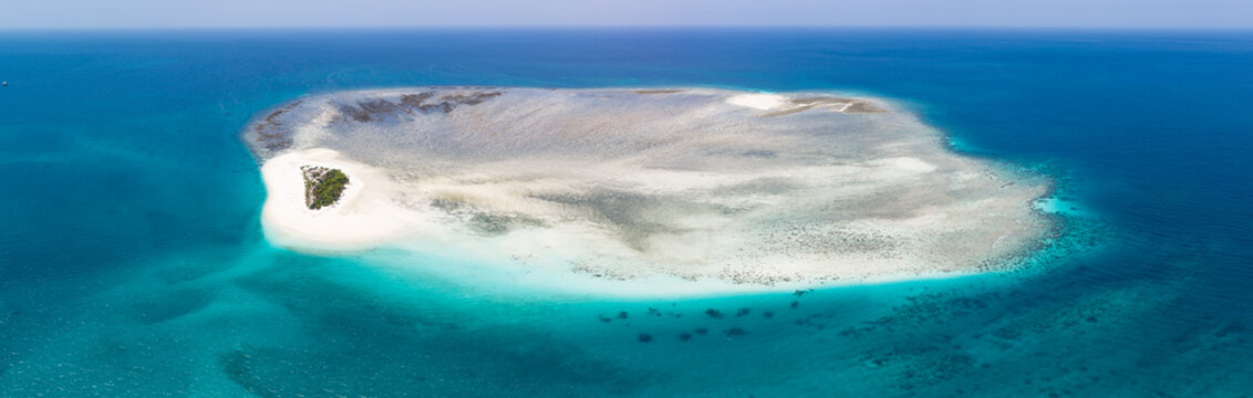 Colorful, turquoise water and coral reef surrounds the tiny, idyllic island of Kaniungan-kecil off the coast of East Kalimantan, Indonesia. This scenic region harbors spectacular marine biodiversity.