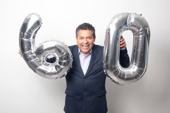 60-year-old Latino man with a dark skin displays 60 shaped balloons to celebrate his birthday and his entry into his old age