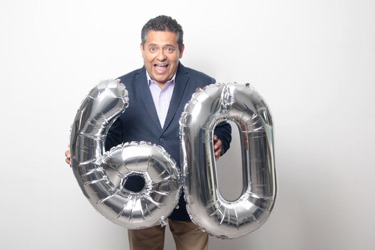 60-year-old Latino man with a dark skin displays 60 shaped balloons to celebrate his birthday and his entry into his old age