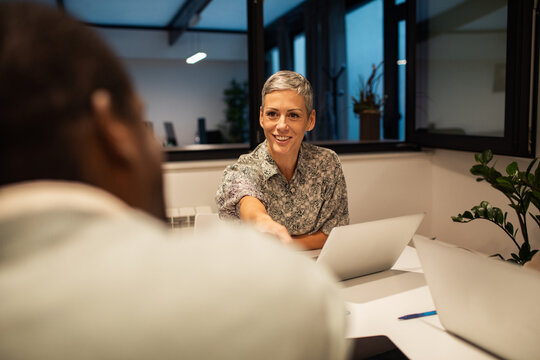 Smiling businesswoman shaking hands during meeting in modern office