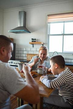 Happy family eating breakfast together in home kitchen