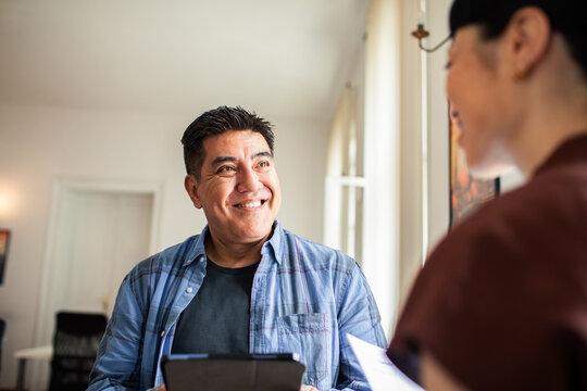 Smiling man talking with coworker in bright home office