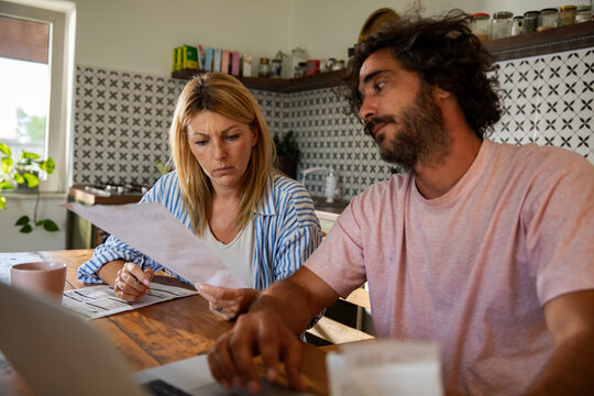 Couple reviewing household bills at kitchen table